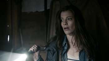 Movie still from “Chernobyl Diaries” (2012), directed by Bradley Parker – A woman holding a flashlight in a dark room; Close Up shot, Over the shoulder angle