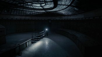Movie still from “Chernobyl Diaries” (2012), directed by Bradley Parker – A person is standing in a dark room with a flashlight; Extreme Wide shot, High angle