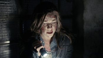 Movie still from “Chernobyl Diaries” (2012), directed by Bradley Parker – A woman holding a flashlight in a dark room; Close Up shot, Over the shoulder angle