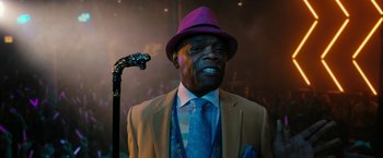 Movie still from “Chi-Raq” (2015), directed by Spike Lee – An older man wearing a suit and purple hat with a cane; Close Up shot, Low angle