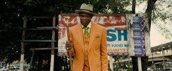 Movie still from “Chi-Raq” (2015), directed by Spike Lee – A man in a suit and hat holding a wooden spoon; Medium shot, Low angle
