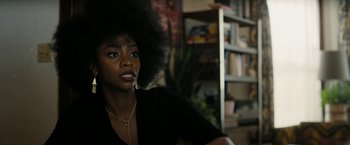 Movie still from “Chi-Raq” (2015), directed by Spike Lee – A woman with a large afro sitting in front of a book shelf; Close Up shot, Over the shoulder angle