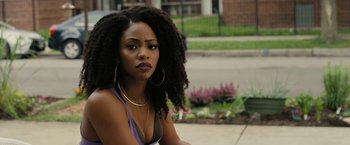 Movie still from “Chi-Raq” (2015), directed by Spike Lee – A woman sitting on the ground in front of a building; Close Up shot, Over the shoulder angle