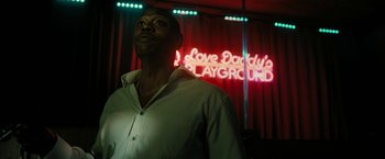 Movie still from “Chi-Raq” (2015), directed by Spike Lee – A man standing in front of a neon sign; Medium shot, Low angle