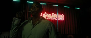 Movie still from “Chi-Raq” (2015), directed by Spike Lee – A man smoking a cigarette in front of a neon sign; Medium shot, Low angle