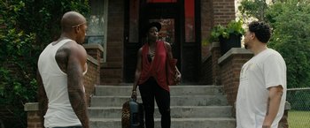 Movie still from “Chi-Raq” (2015), directed by Spike Lee – A woman walking down the stairs holding a suitcase; Wide shot, Low angle