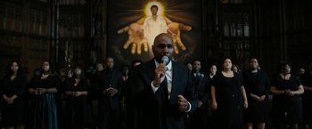 Movie still from “Chi-Raq” (2015), directed by Spike Lee – A group of people standing in front of a painting of jesus; Medium shot, Low angle