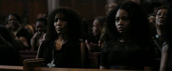 Movie still from “Chi-Raq” (2015), directed by Spike Lee – Two black women sitting in a row in front of a crowd; Close Up shot, High angle