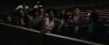 Movie still from “Chi-Raq” (2015), directed by Spike Lee – A group of people sitting in a row of pews in a church; Medium shot, High angle