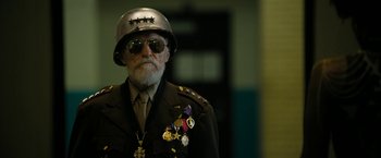 Movie still from “Chi-Raq” (2015), directed by Spike Lee – An older man wearing a military uniform with medals on his hat; Medium shot, Over the shoulder angle