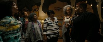 Movie still from “Chi-Raq” (2015), directed by Spike Lee – A group of women standing next to each other in front of a mural; Medium shot, Over the shoulder angle