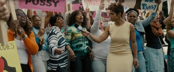 Movie still from “Chi-Raq” (2015), directed by Spike Lee – A group of women holding signs and a microphone; Medium shot, Low angle