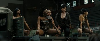 Movie still from “Chi-Raq” (2015), directed by Spike Lee – A group of women standing next to each other on a stage; Medium shot, Over the shoulder angle