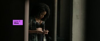 Movie still from “Chi-Raq” (2015), directed by Spike Lee – A woman in a black bra is looking at her cell phone; Medium shot, Over the shoulder angle