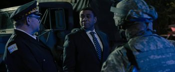 Movie still from “Chi-Raq” (2015), directed by Spike Lee – A man in a suit and tie standing next to a soldier; Medium shot, Over the shoulder angle