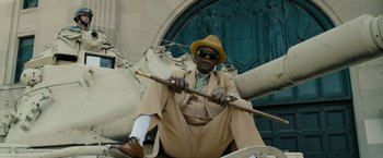 Movie still from “Chi-Raq” (2015), directed by Spike Lee – A man sitting on the ground holding a cane; Wide shot, Low angle