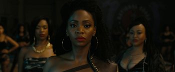 Movie still from “Chi-Raq” (2015), directed by Spike Lee – A person wearing a dress and a necklace; Close Up shot, Over the shoulder angle