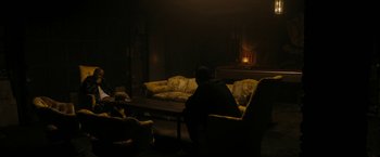 Movie still from “Chi-Raq” (2015), directed by Spike Lee – A man sitting on a couch in a dark living room; Wide shot, High angle