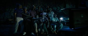 Movie still from “Chi-Raq” (2015), directed by Spike Lee – A group of people sitting in a dark room; Wide shot, High angle