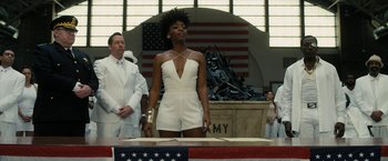 Movie still from “Chi-Raq” (2015), directed by Spike Lee – A woman in a white outfit standing in front of an american flag; Medium shot, Low angle