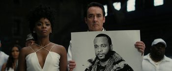 Movie still from “Chi-Raq” (2015), directed by Spike Lee – A man and woman holding up a picture of a man; Close Up shot, Low angle