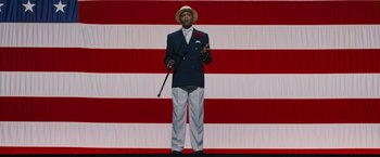 Movie still from “Chi-Raq” (2015), directed by Spike Lee – A man standing in front of an american flag; Wide shot, Low angle