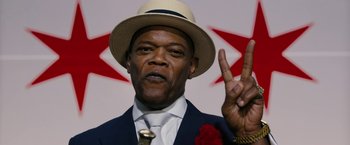 Movie still from “Chi-Raq” (2015), directed by Spike Lee – A man in a suit and hat making a peace sign; Close Up shot, Low angle