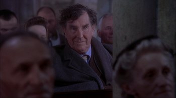 Movie still from “Chocolat” (2000), directed by Lasse Hallström – An older man sitting in a crowd of people; Close Up shot, Over the shoulder angle