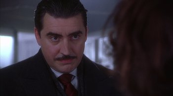 Movie still from “Chocolat” (2000), directed by Lasse Hallström – A person wearing a suit and a tie; Close Up shot, Over the shoulder angle