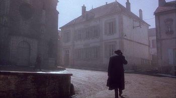 Movie still from “Chocolat” (2000), directed by Lasse Hallström – A person standing on the street in front of a building; Extreme Wide shot, Low angle