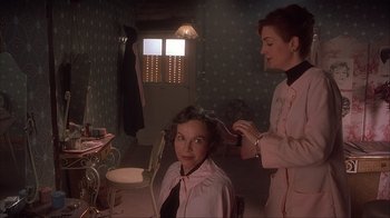 Movie still from “Chocolat” (2000), directed by Lasse Hallström – A woman getting her hair done by a stylist in a room; Medium shot, Over the shoulder angle