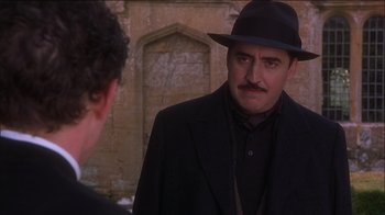 Movie still from “Chocolat” (2000), directed by Lasse Hallström – A man wearing a hat and a black suit; Close Up shot, Over the shoulder angle