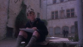Movie still from “Chocolat” (2000), directed by Lasse Hallström – A young man sitting on the ground writing on a piece of paper; Medium shot, Low angle