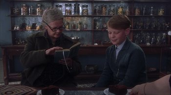 Movie still from “Chocolat” (2000), directed by Lasse Hallström – An older woman reading a book to a young boy; Medium shot, Over the shoulder angle