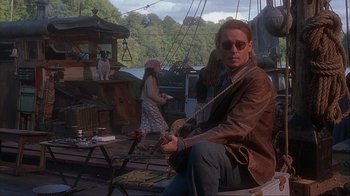 Movie still from “Chocolat” (2000), directed by Lasse Hallström – A man sitting on top of a boat next to a woman; Wide shot, Low angle