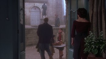 Movie still from “Chocolat” (2000), directed by Lasse Hallström – A group of people standing around a table in front of a building; Wide shot, Over the shoulder angle