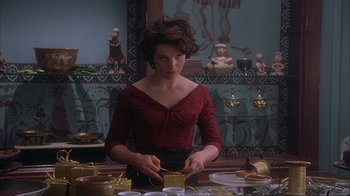 Movie still from “Chocolat” (2000), directed by Lasse Hallström – A woman in a red shirt is cutting a cake; Medium shot, Over the shoulder angle