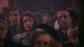 Movie still from “Chocolat” (2000), directed by Lasse Hallström – A woman and a man are sitting in a crowd; Close Up shot, Low angle