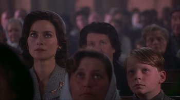 Movie still from “Chocolat” (2000), directed by Lasse Hallström – A group of people sitting in front of a crowd of people; Close Up shot, Over the shoulder angle