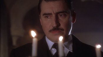 Movie still from “Chocolat” (2000), directed by Lasse Hallström – A person wearing a suit and tie; Close Up shot, Low angle