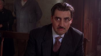 Movie still from “Chocolat” (2000), directed by Lasse Hallström – A person wearing a suit and tie; Close Up shot, Low angle