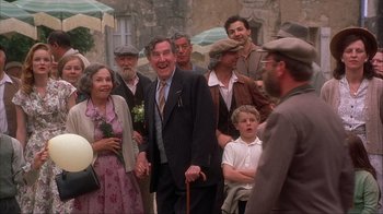 Movie still from “Chocolat” (2000), directed by Lasse Hallström – A group of people standing around each other in the street; Medium shot, Low angle