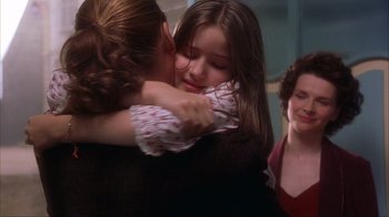 Movie still from “Chocolat” (2000), directed by Lasse Hallström – A woman hugging a young girl while another woman looks on; Close Up shot, Over the shoulder angle