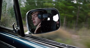 Movie still from “Chronicle” (2012), directed by Josh Trank – A man is taking a picture in the side view mirror of a car; Close Up shot, Over the shoulder angle