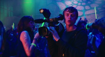 Movie still from “Chronicle” (2012), directed by Josh Trank – A man holding a video camera in front of a crowd of onlookers; Medium shot, Over the shoulder angle