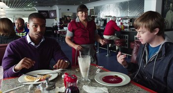Movie still from “Chronicle” (2012), directed by Josh Trank – A woman standing at a table in front of a glass of milk; Medium shot, Over the shoulder angle