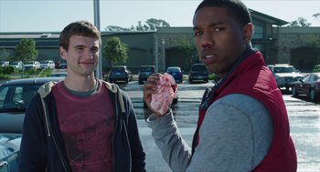 Movie still from “Chronicle” (2012), directed by Josh Trank – Two young men standing next to each other holding a piece of meat; Medium shot, Over the shoulder angle