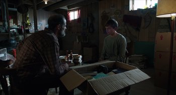 Movie still from “Chronicle” (2012), directed by Josh Trank – Two men sitting at a table in a room with boxes; Medium shot, Over the shoulder angle