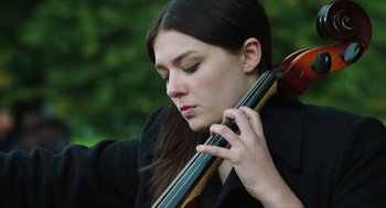 Movie still from “Chronicle” (2012), directed by Josh Trank – A young woman holding a cello while wearing a black jacket; Close Up shot, Low angle