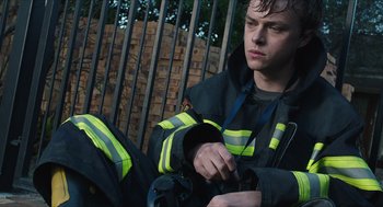 Movie still from “Chronicle” (2012), directed by Josh Trank – A man sitting on the ground wearing a black and yellow jacket; Medium shot, Low angle